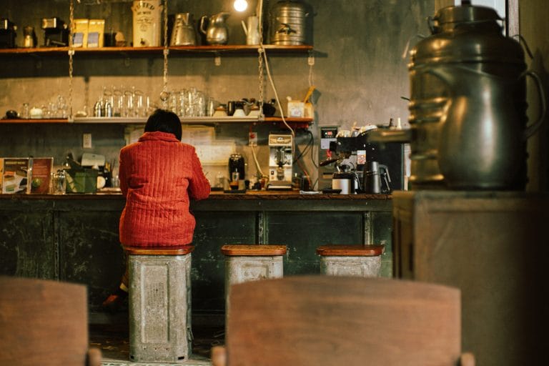women sitting on a chair wearing red coat in a cafe
