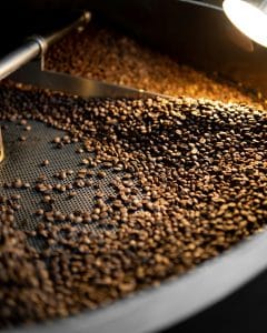 coffee beans being roasted in a metal surface machine