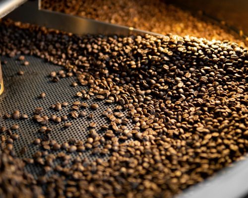 coffee beans being roasted in a metal surface machine